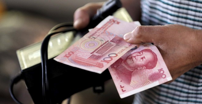 Una mujer sostiene dos bitteletes de 100 yuanes en un mercado de Beijing. REUTERS/Jason Lee