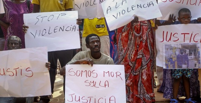 Inmigrantes senegaleses muestran pancartas contra la los Mossos D'esquadra en la manifestació en Salou para protestar por la muerte de un compatriota en una operación contra el 'top manta'. AFP PHOTO / QUIQUE GARCIA