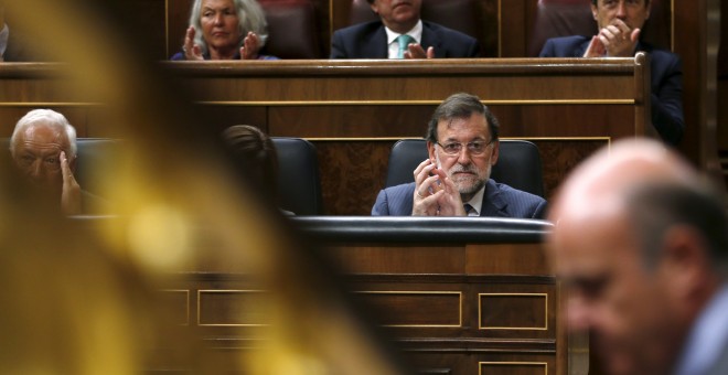 El presidente del Gobierno, Mariano Rajoy, observa al ministro de Economía, Luis de Guindos, durante su intervención en el pleno del Congreso.- REUTERS