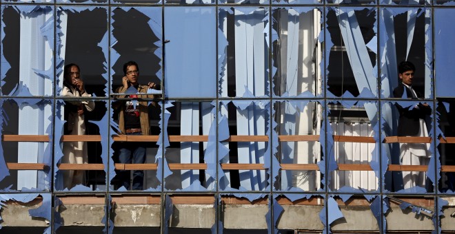 Un hombre mira a través de las ventanas rotas por el atentado de este sábado en Kabul.-REUTERS