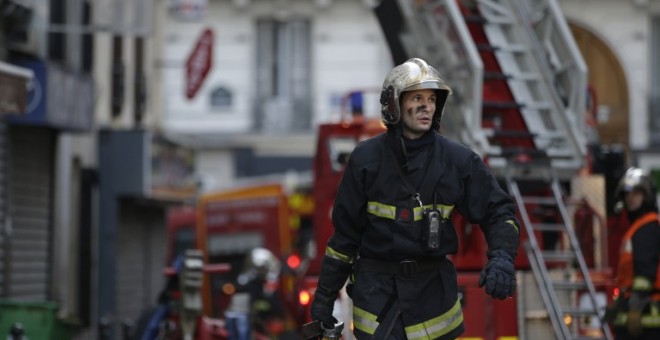 Un bombero trabaja en las labores de extinción del incendio declarado en un bloque de viviendas en París. /AFP