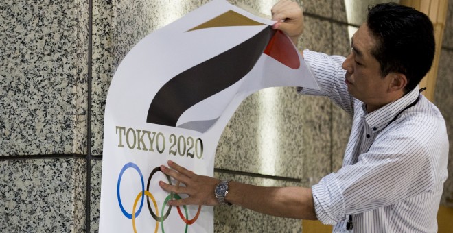 Un empleado retira un cartel con el logotipo de Tokio 2020, que tendrá que ser sustituido. /REUTERS