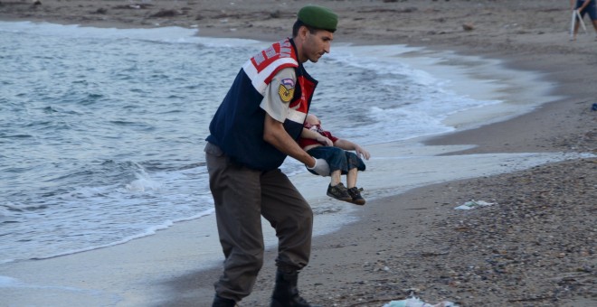 Un agente de la gendarmería turca lleva el cuerpo de un niño que formaba parte del grupo de refugiados sirios que se han ahogado intentando llegar a la isla de Kos. REUTERS/Nilufer Demir