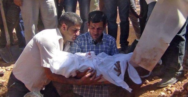 Abdulá Kurdi, padre de Aylan Kurdi, sostiene el cuerpo de su hijo de tres años durante el entierro. / (EFE)
