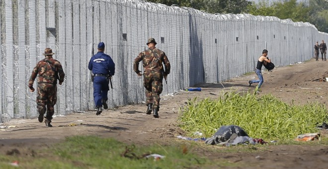Un migrante cruza la frontera de Hungría mientras soldados y policías tratan de atraparlo. REUTERS