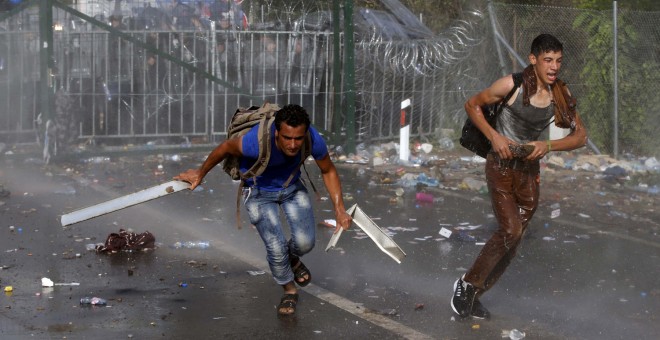 Un grupo de inmigrantes protesta en la frontera mientras la Policía húngara les rocía con gases y cañones de agua. REUTERS