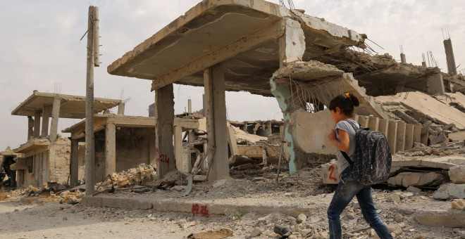 Los niños sirios caminan al lado de los escombros en su camino al colegio en el segundo día del nuevo año escolar, el 6 de octubre de 2015, en la ciudad kurda de Siria de Kobane. AFP PHOTO / delil Souleiman