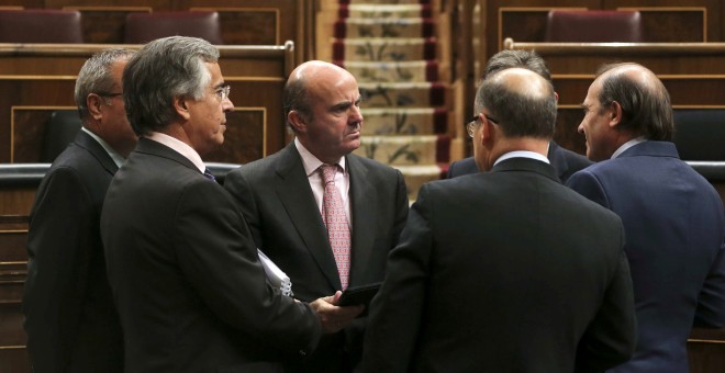 El ministro de Economía, Luis de Guindos, el pasado miércoles, rodeado de diputados del PP en el hemiciclo del Congreso de los Diputados. EFE
