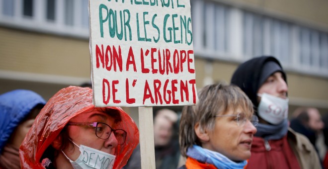 Una activista sostiene una pancarta en la que se puede leer 'Sí a la Europa de las personas, no a la Europa del dinero' ante la sede de la UE, en Bruselas. EFE/Olivier Hoslet