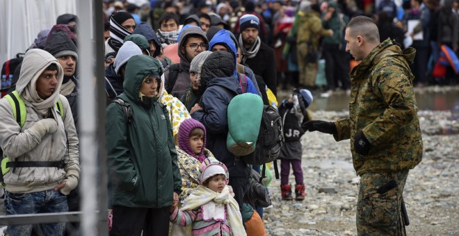 Un agente de policía macedonio conversa con un grupo de refugiados antes de que éstos puedan subir a un tren que se dirige hacia a la frontera serbia, cerca de la ciudad de Gevgelija, Macedonia. EFE