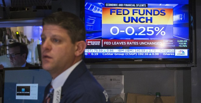 Un operador de la bolsa de Wall Street junto a un monitor que muestra la noticia de la decisión de la Reserva Federal de no tocar todavía los tipos de interés en EEUU. REUTERS/Lucas Jackson