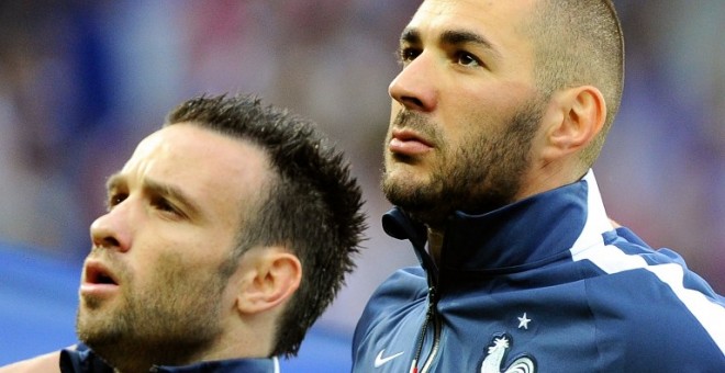 Benzema y Valbuena escuchan junto el himno francés en un partido de su selección. /AFP