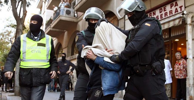 Uno de los tres detenidos por la Guardia Civil, implicados en una red de captación y envío de personas para su incorporación a la organización terrorista DAESH, sale custodiado por agentes de la benemérita en la calle Marina de Barcelona. EFE/TONI ALBIR