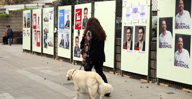 Una mujer pasa por delante de carteles electorales de los distintos candidatos a Presidente de Gobierno para las elecciones generales del próximo domingo en Santurce (Vizcaya), durante la campaña electoral para las elecciones generales del próximo 20-D. E