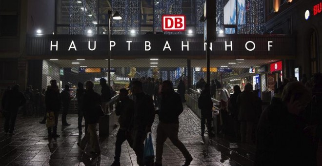 Varias personas caminan junto a la estación de tren de Múnich (Alemania), cerrada después de conocerse que la organización terrorista Estado Islámico (EI) tenía planificado perpetrar un atentado suicida durante la nochevieja. EFE/Sven Hoppe