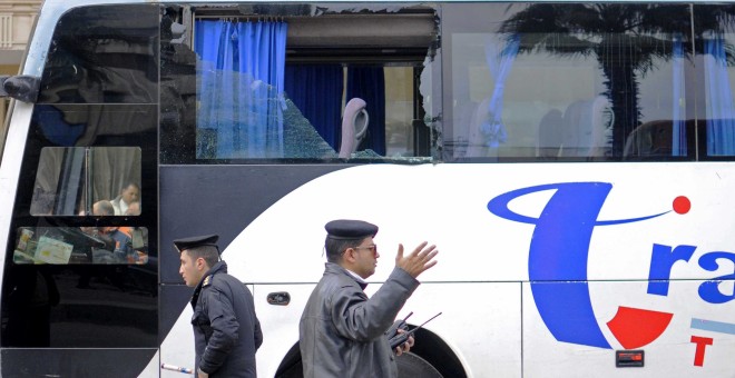 Dos policías vigilan junto a un autobús con una ventanilla dañada tras el ataque de varios hombres armados, cerca de las pirámides de Giza, Egipto.- EFE