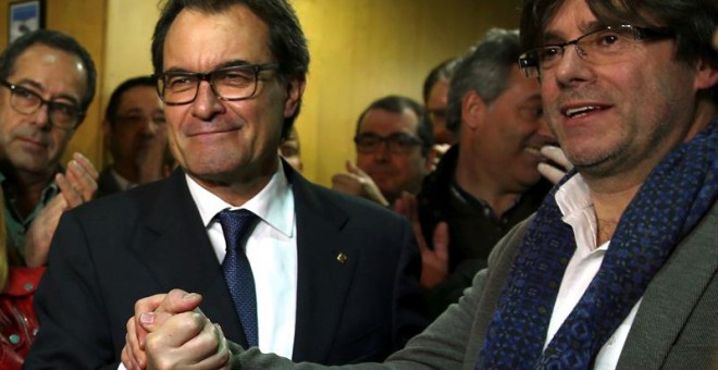 El presidente catalán en funciones, Artur Mas (i), estrecha la mano del alcalde de Girona, Carles Puigdemont (d), a su llegada a la sede de CDC tras la rueda de prensa que ha ofrecido hoy en el Palau de la Generalitat en la que ha anunciado públicamente s