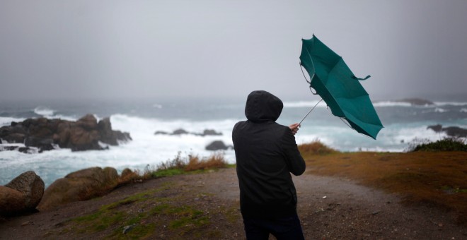 Un hombre ve como el viento le dobla el paraguas en A Coruña. EFE