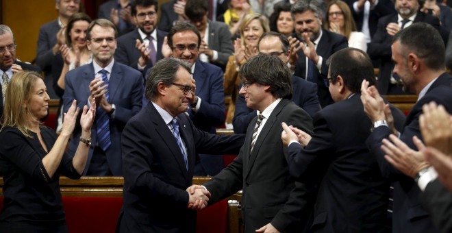 Artur Mas saluda al nuevo president de le Generalitat, Carles Puigdemont al término del pleno de investidura en el Parlament. - REUTERS