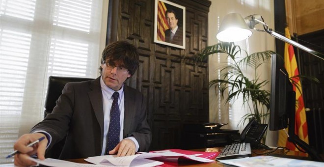 El nuevo presidente electo catalán, Carles Puigdemont, en su despacho del Ayuntamiento de Girona tras hacer oficial su renuncia a la alcaldía de la ciudad. EFE/David Borrat