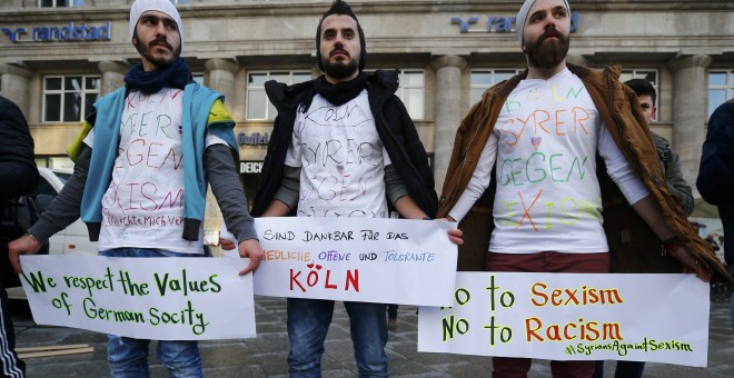 Tres hombres de origen sirios portan pancartas en contra de los ataques de la pasada Nochevieja en Colonia. - REUTERS