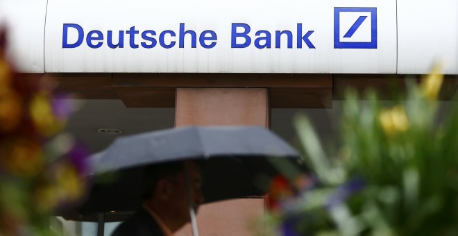 Un hombre bajo un paraguas pasa por delante de una sucursal de Deutsche Bank en la localidad alemana de Hanau. REUTERS/Kai Pfaffenbach