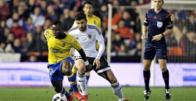 El centrocampista ghanés de Las Palmas Wakaso Mubarak (i) con el balón ante el defensa del Valencia CF, Antonio Barragán. /EFE
