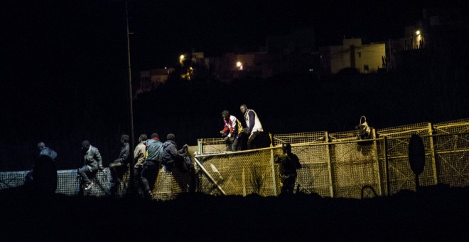 Varios emigrantes se sientan en la parte superior de la valla fronteriza de Melilla en  un intento de cruzar a territorio español. REUTERS / Jesús Blasco de Avellaneda