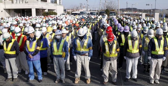 Trabajadores de la descontaminacion de la zona de  Fukushima guardan un minuto de silencio en la ceremonia en recuerdo de las víctmas del tsunami de marzo de 2011. REUTERS/Kyodo