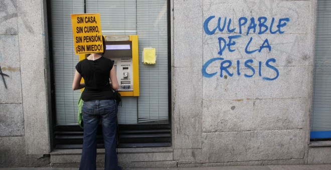 Una participante en una manifestación contra la austeridad, en un cajero automático en Madrid. REUTERS
