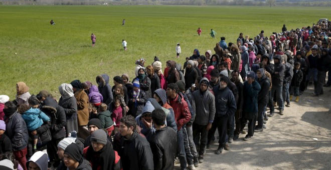 Decenas de refugiados esperan para recibir comida en las inmediaciones de Idomeni. REUTERS/Marko Djurica