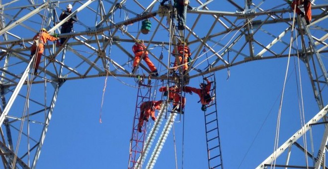 Empleados de Abengoa realizando trabajos de construcción en una torre de línea de transmisión en Chile.