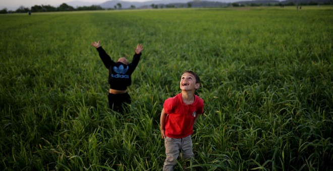 Unos niños miran al cielo mientras juegan con una cometa junto a un campo de refugiados en la frontera entre Grecia y Macedonia cerca de Idomeni.  REUTERS/Stoyan Nenov