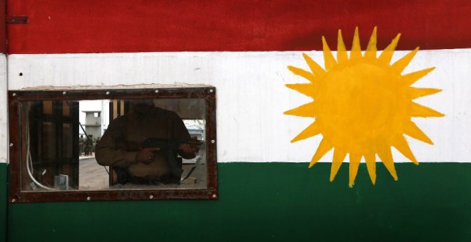 Un 'peshmerga' hace guardia en un control con la bandera kurda en la ciudad de Khazir. - AFP