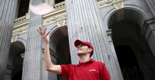 Un empleado de Telepizza hace malabares con la masa en la Bolsa de Madrid, el día de la salida a bolsa de la cadena de comida rápida. REUTERS/Andrea Comas