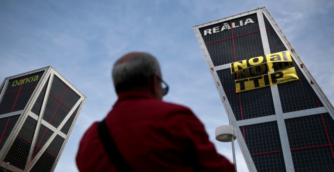 Un hombre oberva el cartel contra el TTIP colgado por activistas de Greenpeace. REUTERS/Andrea Comas