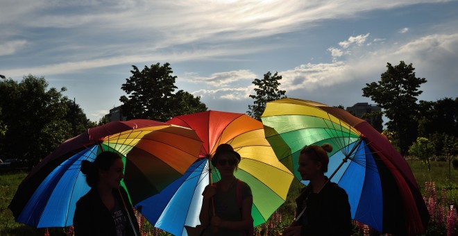Personas sostienen paraguas arco iris para celebrar el Día Internacional contra la Homofobia frente al edificio del Parlamento rumano en Bucarest. DANIEL MIHAILESCU / AFP