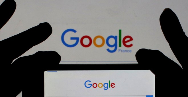 Una mujer sostiene la cámara de su smartphone frente a la portada de Google en Francia. REUTERS/Eric Gaillard