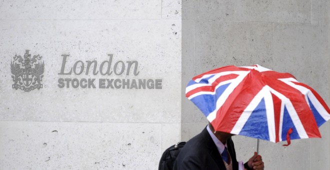 Una persona con un paraguas con los colores de la bandera británica delante de la entrada de la Bolsa de Londres. REUTERS/Toby Melville