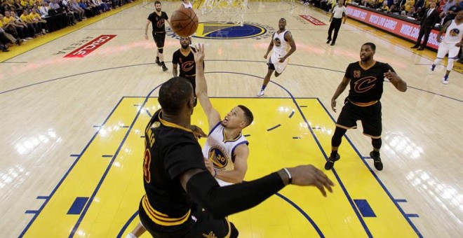 Stephen Curry (c) lucha por el balón con LeBron James en el quinto partido de la final.