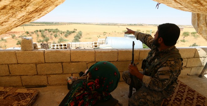 Un combatiente de las Fuerzas Democráticas Siria (SDF) problemas mientras está sentado en posición de mirar hacia fuera en el área rural occidental de Manbij, en Alepo gobernación, Siria, 13 de junio de 2016. REUTERS / Rodi Said