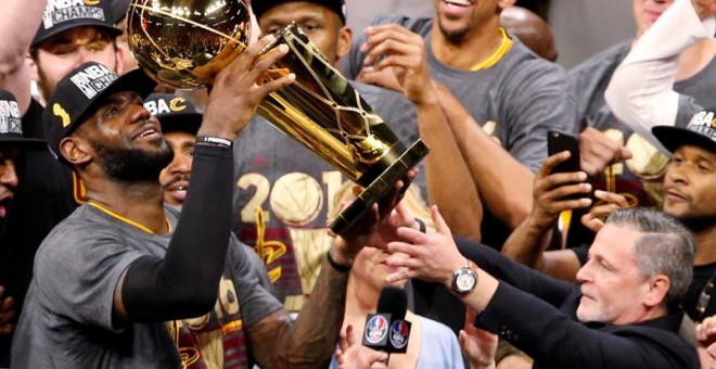 La estrella de los Cavaliers, LeBron James, levanta el trofeo de campeones de la NBA. EFE/JOHN G. MABANGLO