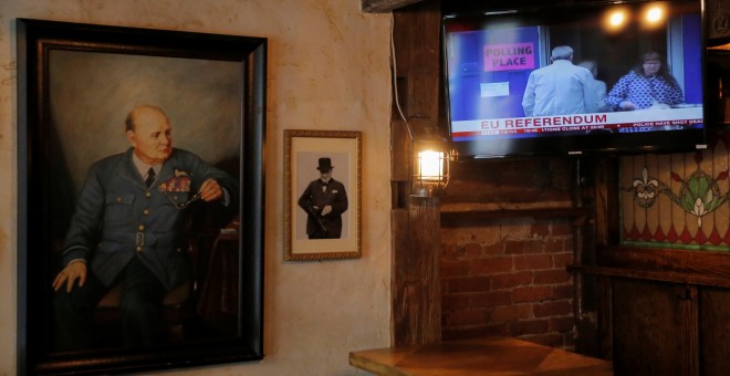 A painting of former British Prime Minister Winston Churchill hangs beside a television broadcasting Brexit polling at The Churchill Tavern, a British themed bar, on the day Britain votes whether or not to remain in the European Union, in the Manhattan bo
