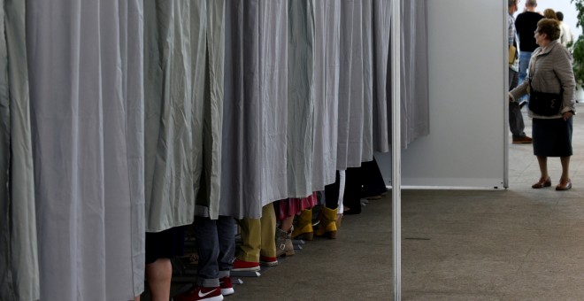 Varias personas en las cabinas preparan sus votos para el 26-J. REUTERS/Eloy Alonso
