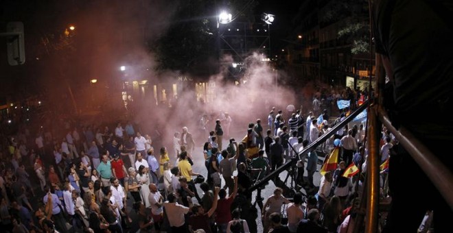 Varias personas disfrazados de presos lanzan botes de humo en los alrededores de la calle Génova de Madrid./ EFE