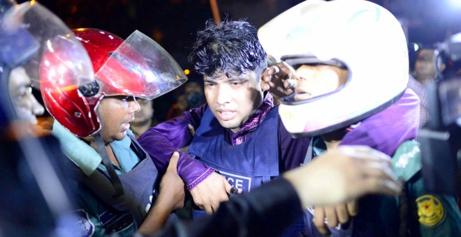 Un policía herido es sacado del restaurante atacado por un grupo armado en Dacca. /REUTERS