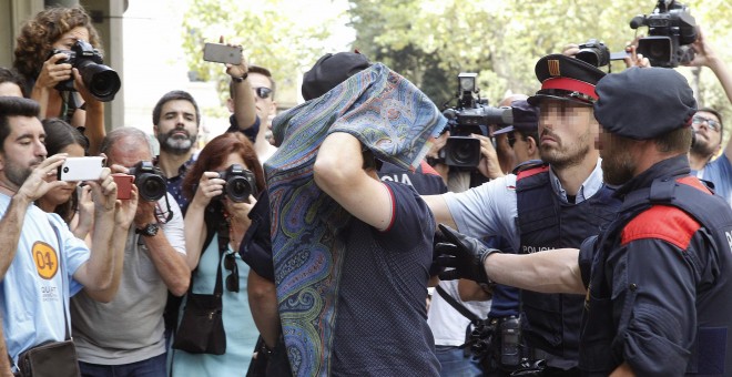 Mossos d'Esquadra y Policía Nacional custodian a una de las personas detenidas hoy en una operación en Barcelona en la que se prevé detener a once personas acusadas de blanquear 10 millones de euros vinculados al crimen organizado con la compra de inmuebl