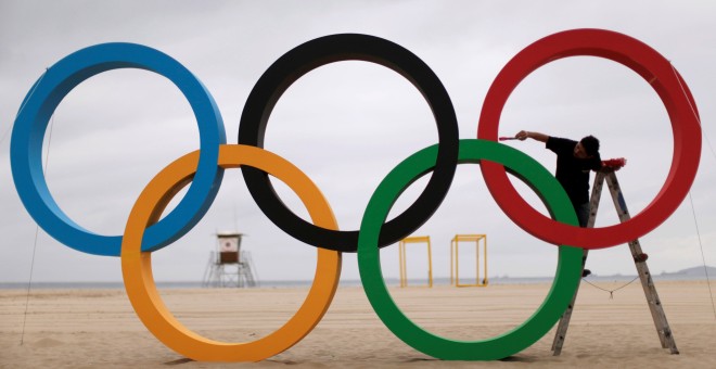 Un hombre pinta los anillos olímpicos en la playa de Copacabana para ultimar los preparativos de los juegos olímpicos de Río de Janeiro/REUTERS