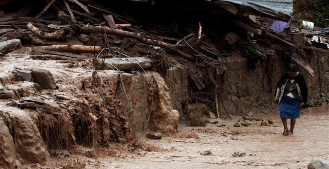 Una mujer camina frente a viviendas afectadas tras un deslizamiento producido por las intensas lluvias propiciadas por la tormenta Earl, en el municipio de Huahuchinango (México).