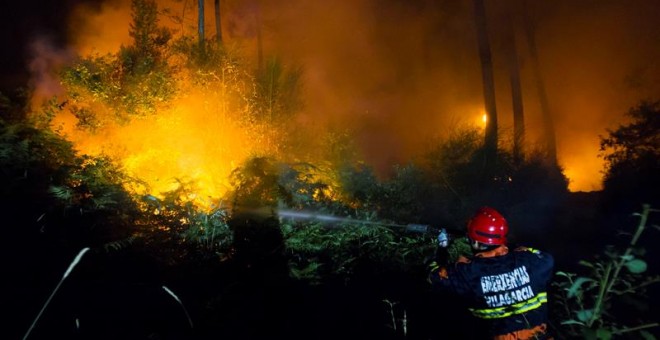 Operarios de Protección Civil de Vilagarcía luchan contra el incendio forestal declarado en Castrogudín, en la provincia de Pontevedra, que ha obligado esta madrugada a cortar la via de alta capacidad VG-4-7 que bordea la localidad./ EFE